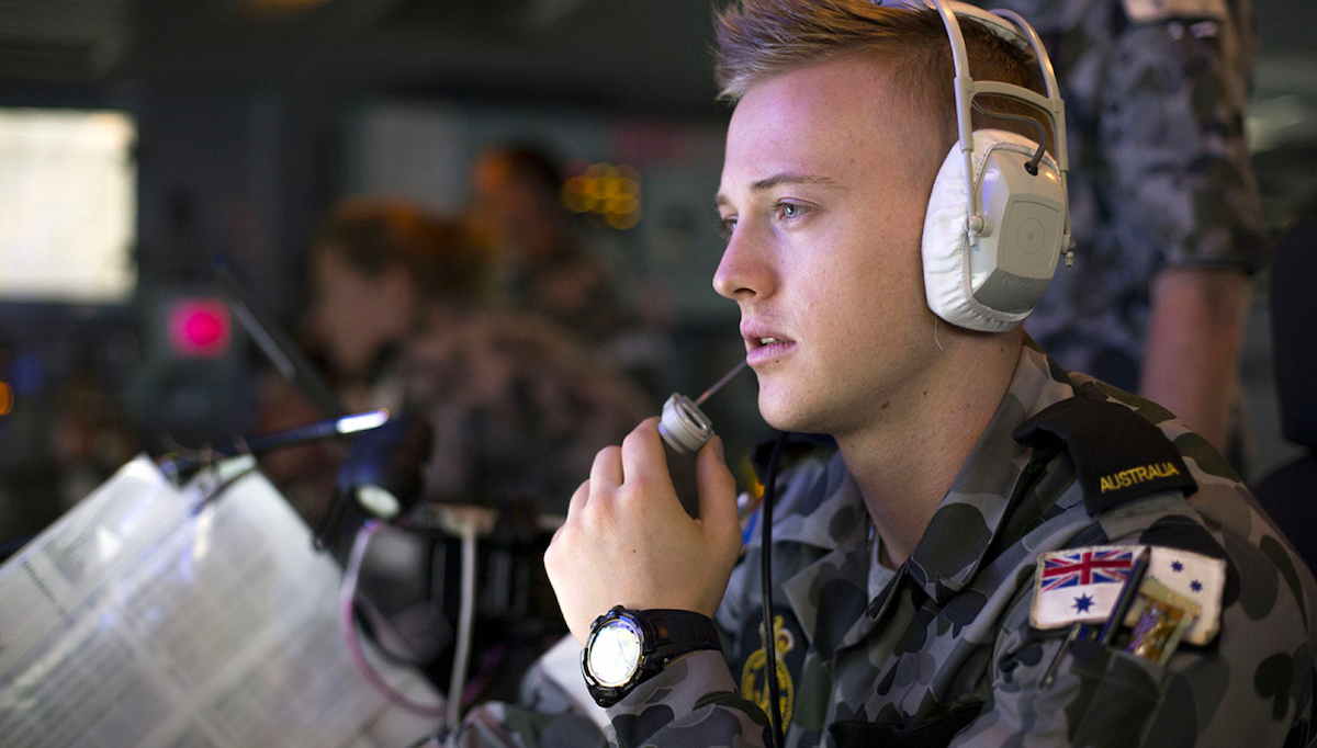 A member of the Navy listens in on headphones.